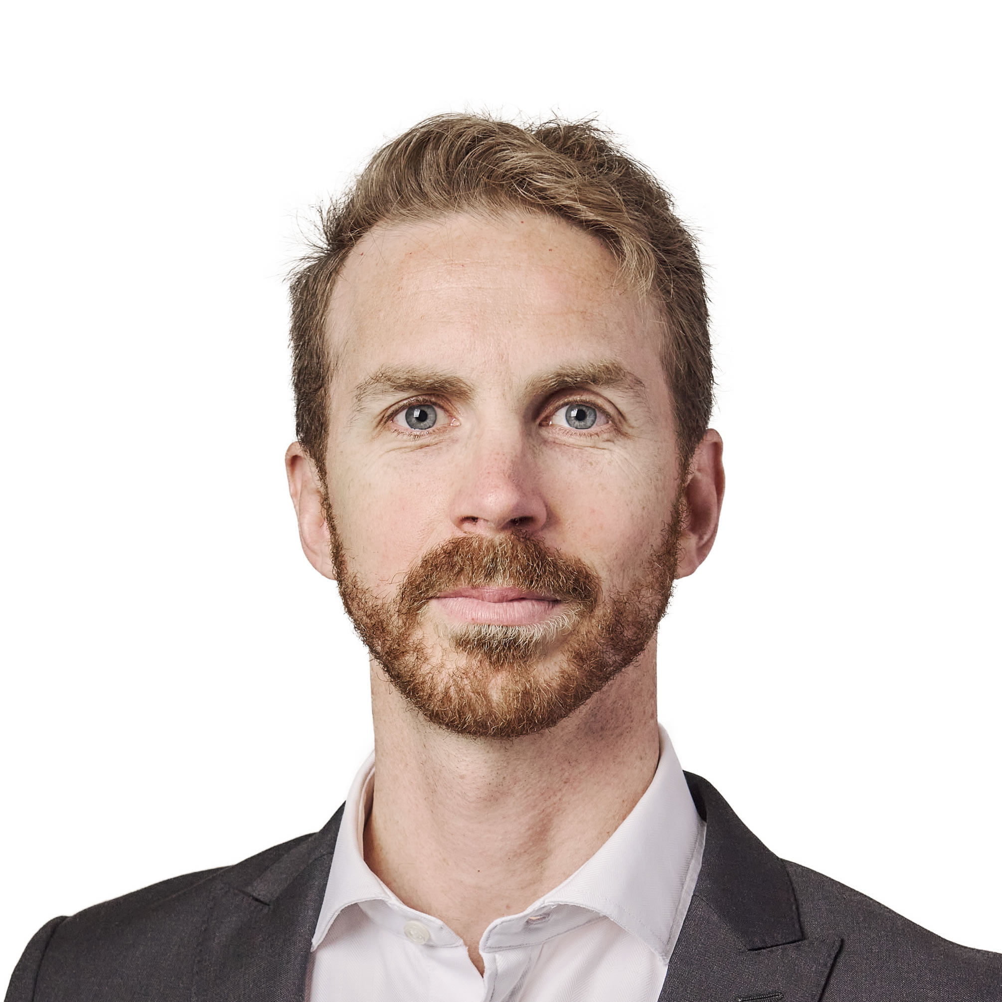 Portrait of a man with light brown hair and a beard, wearing a black suit and white shirt, against a plain white background.
