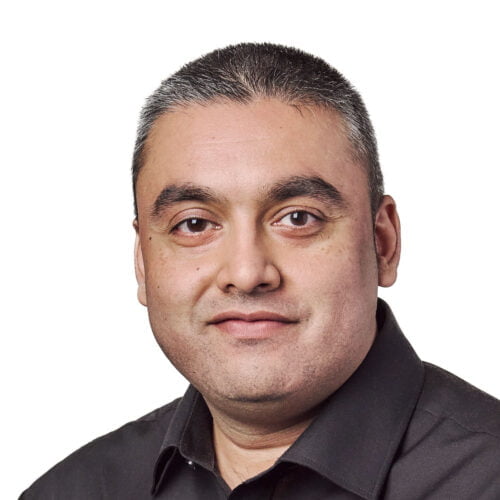 Portrait of a middle-aged man with short dark hair and a serious expression, wearing a black shirt against a white background.