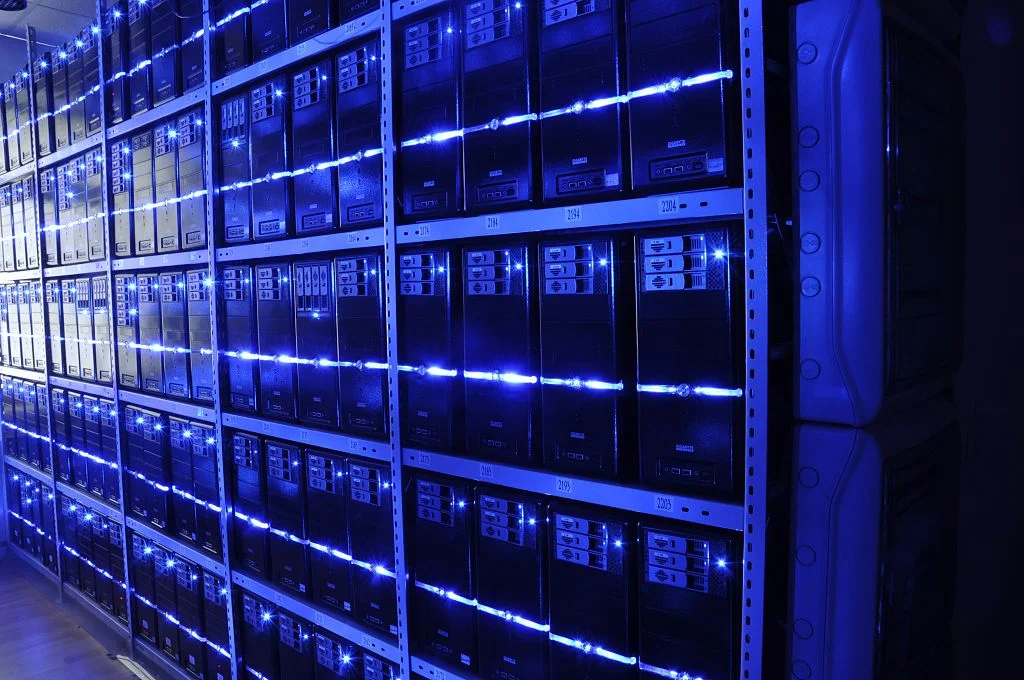 A modern data center with rows of servers illuminated by blue led lights.