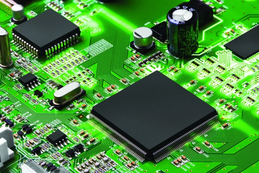 Close-up of a green circuit board featuring various IT crisis management components like microchips, capacitors, and resistors.