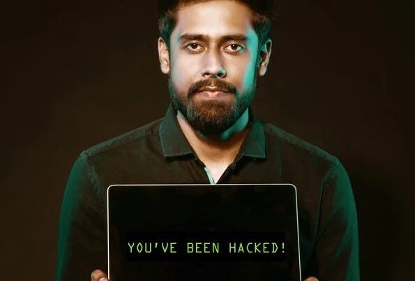 A man with a beard holds a laptop displaying the message "you've been hacked!" on a dark background, symbolizing threats in cyber security for businesses.