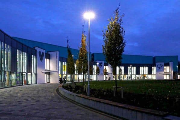 Modern leisure centre with large "tv" logo illuminated at dusk, featuring a well-lit entrance and landscaped pathway.