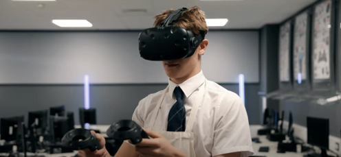 Young man in a shirt and tie using a virtual reality headset and controllers in a modern office environment.