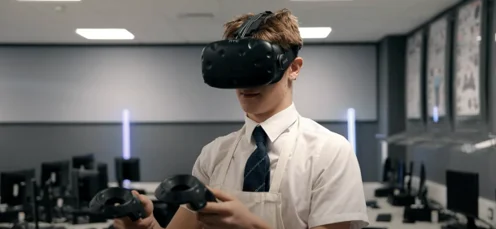 Young man in a shirt and tie using a virtual reality headset and controllers in a modern office environment.