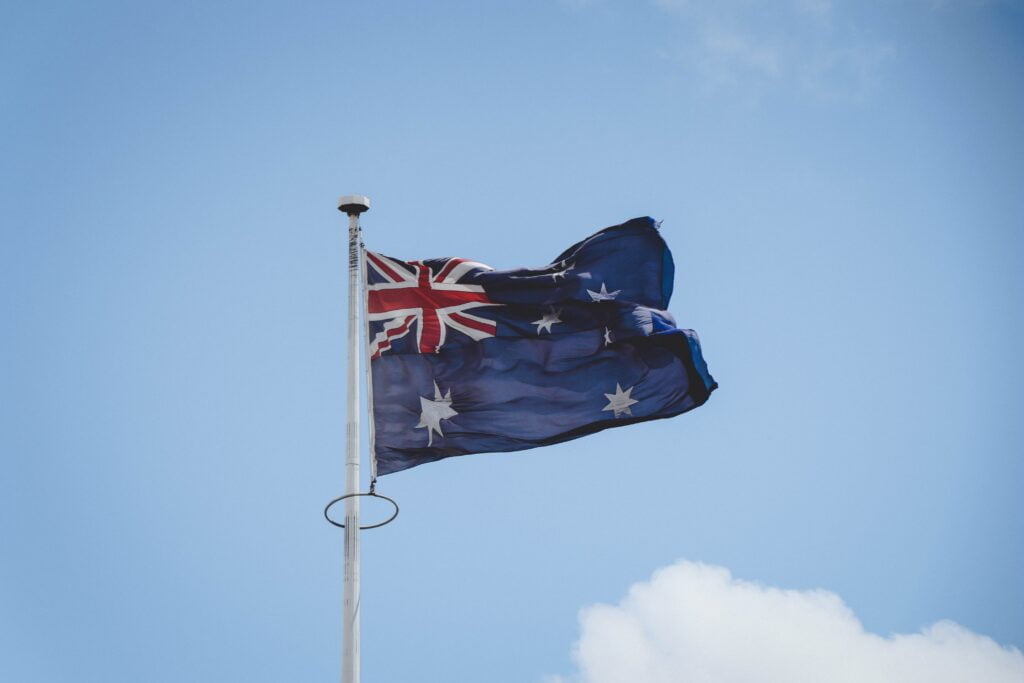 Australian flag waving against a blue sky with light clouds.
