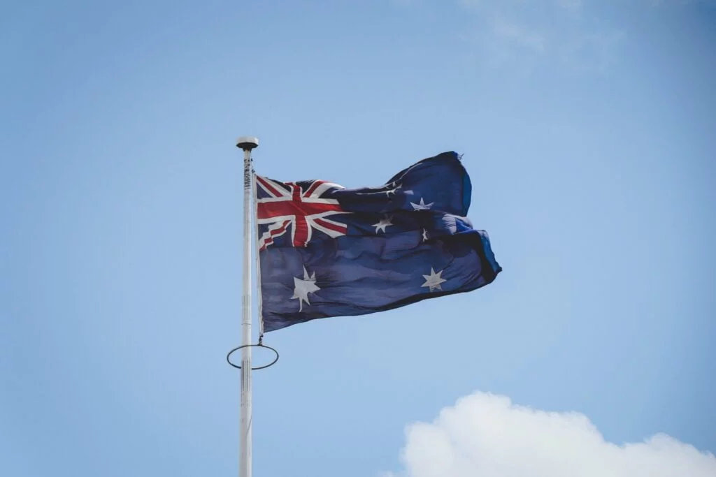 Australian flag waving against a blue sky with light clouds.