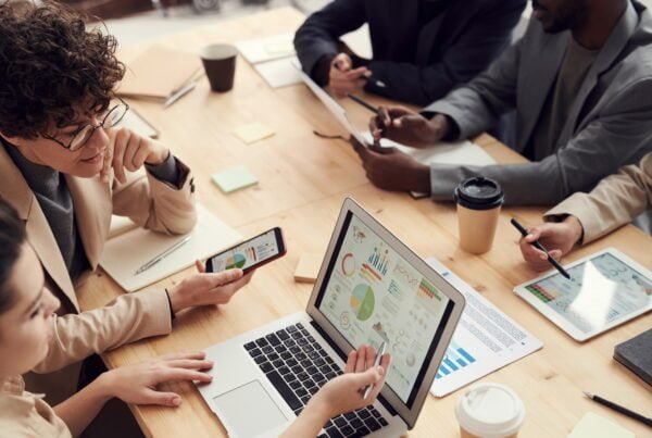 Diverse group of professionals analyzing data on a laptop during a business meeting.