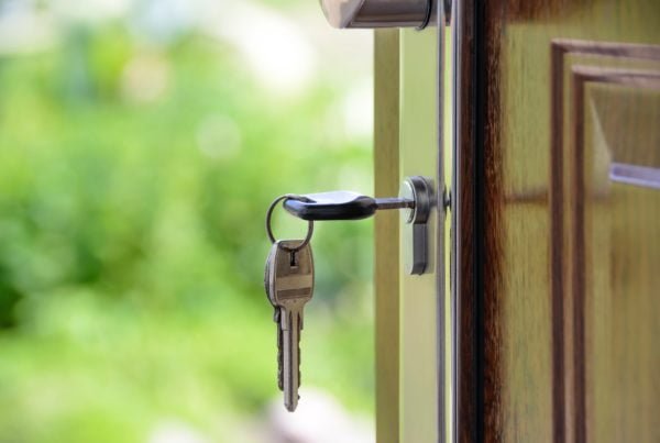 Keys hanging in an open door lock with a blurred green background, symbolizing secure SaaS apps.