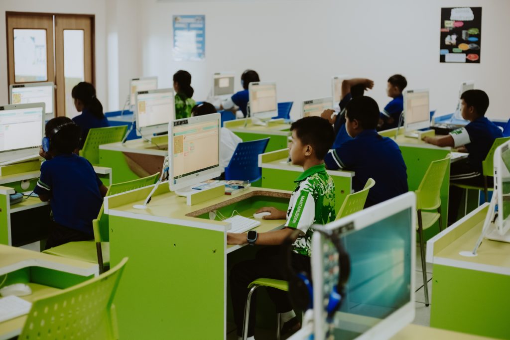 Students in a computer lab working on desktop computers, with one boy facing away from his screen.