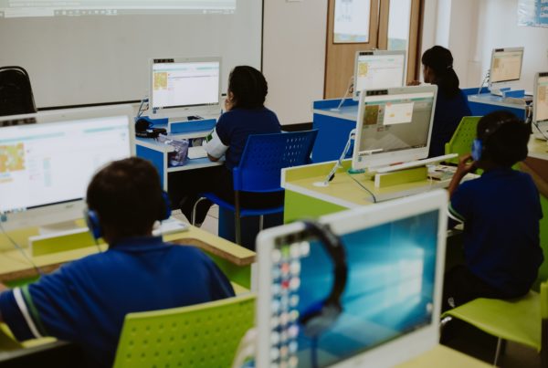 Students in blue uniforms working on computers in a school computer lab.