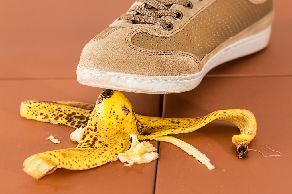 A brown sneaker about to step on a peeled banana on a tiled floor, emphasizing the importance of backup and restore strategies in avoiding mishaps.