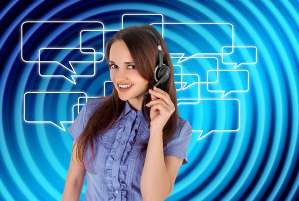 A woman with a headset smiles against a digital background with blue swirls and speech bubbles.