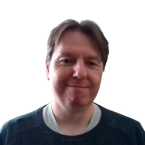 Meet the team: Middle-aged man with a slight smile, wearing a blue and grey shirt, against a light background.